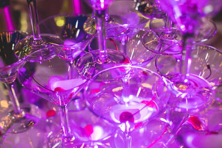 Glasses with alcoholic beverages in the pyramid, filling and pouring beautiful pyramid line of different colored alcohol cocktails with champagne on party, catering banquet tableの写真素材