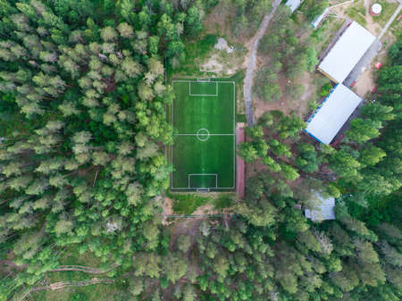 Aerial drone view of football soccer pitch field, green grass summer vibrant pitch playground in the forest, hidden in the green woodsの写真素材