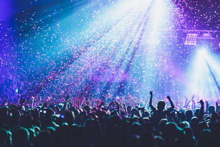 A crowded concert hall with scene stage lights, rock show performance, with people silhouette,...