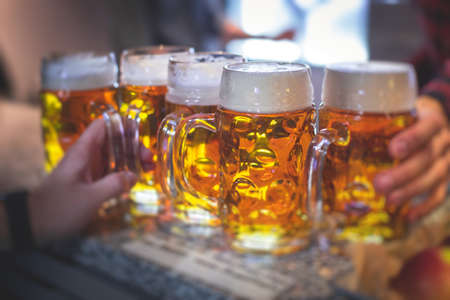 Beer festival view, gold colored beer glasses assortment in a pub, german unfiltered wheat beer, people cheering up and toasting with glasses of light lager, Oktoberfest viewの写真素材