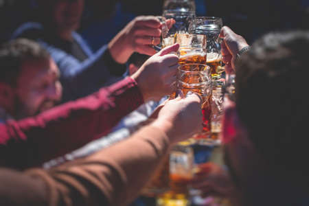 Beer festival view, gold colored beer glasses assortment in a pub, german unfiltered wheat beer, people cheering up and toasting with glasses of light lager, Oktoberfest viewの写真素材