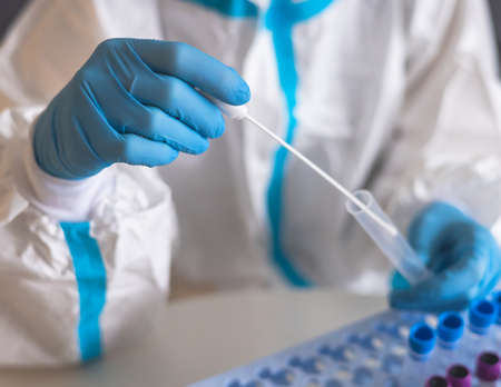 Process of coronavirus PCR antigen testing examination by nurse medic in laboratory lab, COVID-19 swab collection kit, test tube for taking OP NP patient specimen sample, patient receiving a testの写真素材