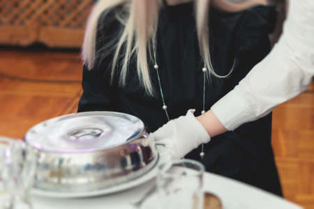 Process of serving luxury dinner in a cloche plate dish with a lid, waiter serving main course meal...