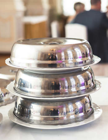 Process of serving luxury dinner in a cloche plate dish with a lid, waiter serving main course meal under silver platter on a banquet in a restaurant or hotel, serving dish food coverの写真素材