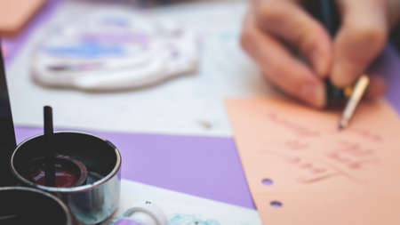 Process of calligraphy handwriting with an ink fountain pen feather, calligrapher practicing writing...