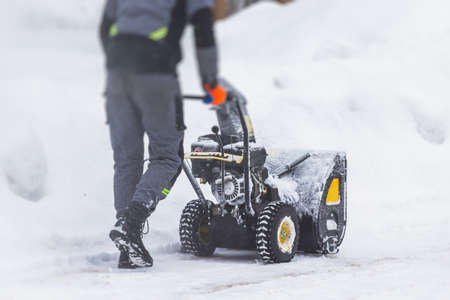 Professional climber rope access worker with a shovel removes snow and take off icicle from high rise building, industrial mountaineers working at heights, manual snow removal, cleaning roofsの写真素材