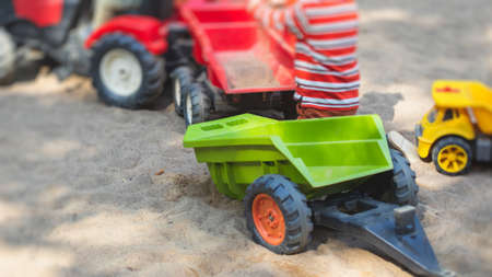 Children playing in the sandbox sandpit, kids with toy car vehicle, playground in a kindergarten day...