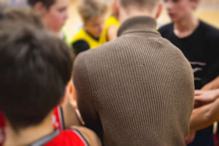 Junior young basketball team with a coach, group of kids children team having training and team talk speach with trainer instructor, basket or football coach on a courtの写真素材
