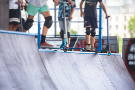 Skate park view with kids on a kick scooter doing tricks and stunts, boys in a skate park riding bmx...