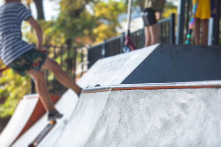 Skate park view with kids on a kick scooter doing tricks and stunts, boys in a skate park riding bmx...