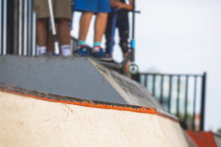 Skate park view with kids on a kick scooter doing tricks and stunts, boys in a skate park riding bmx bike and skate, playing and enjoying summer on a new ramp, teenagers skateboarders and bmx ridersの写真素材