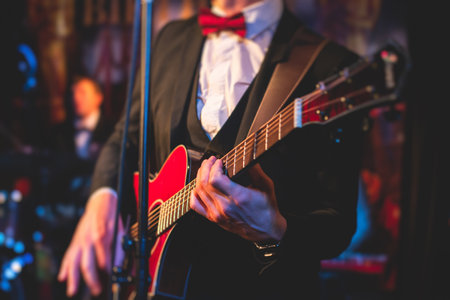 Concert view of electric guitar player with vocalist and musical jazz band orchestra performing in the background, guitarist on the stageの写真素材
