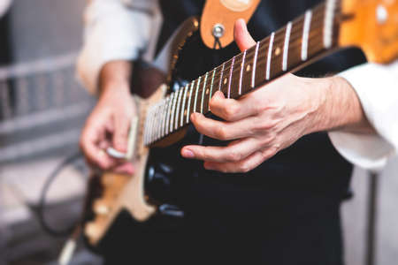 Concert view of an electric guitar player with vocalist and musical jazz rock band orchestra performing in a background, guitarist on stageの写真素材