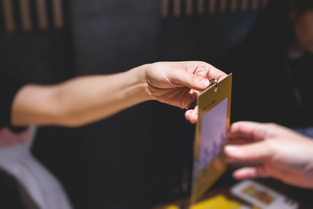 Process of checking in on a conference congress forum event, the registration desk table, visitors and attendees receiving a name badge and entrance wristband bracelet and register electronic ticketの写真素材