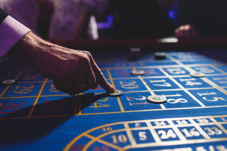 Vibrant casino table with roulette in motion, with casino chips, tokens, the hand of croupier,...