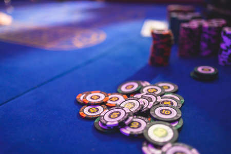 Vibrant casino table with roulette in motion, with casino chips, tokens, the hand of croupier, dollar bill money and a group of gambling rich wealthy people playing bet in the backgroundの写真素材