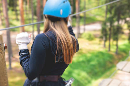 View of high ropes course, process of climbing in amusement acitivity rope park, passing obstacles and zip line on heights in climbing safety equipment gear between the trees, summer dayの写真素材