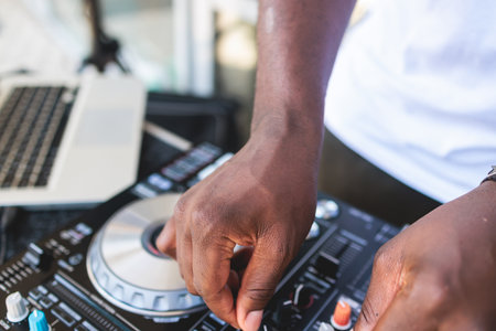 View of Dj mixer and vinyl plate with headphones on a table with african american DJ playing on...