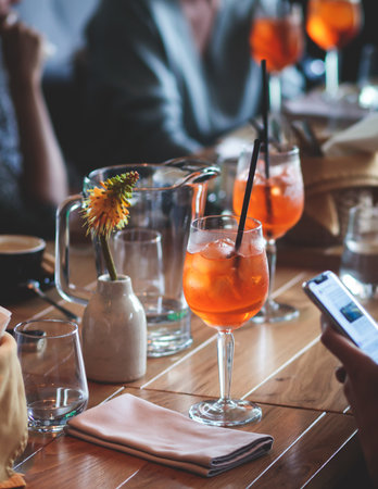 View of alcohol setting on catering banquet table, row line of orange red colored aperitif alcohol cocktails on a party, negroni, spritz and others on a decorated catering bouquet table eventの写真素材