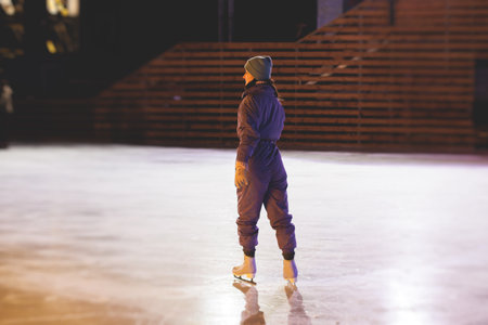 Girl skating on the ice rink arena with happy people around, concept of ice skating in winter, winter activities, holiday christmas time, with new year decoration and illuminationの写真素材