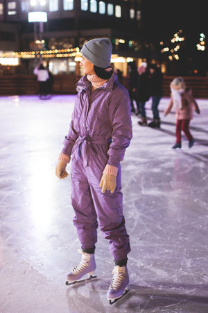 Girl skating on the ice rink arena with happy people around, concept of ice skating in winter,...
