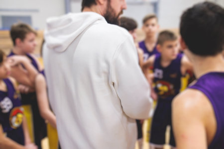 Junior young basketball team with a coach, group of kids children team having training and team talk speach with trainer instructor, basket coach explaining the game plan tactics on a clipboardの写真素材