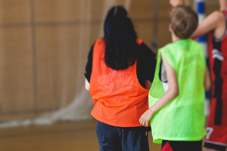 Junior teenage school team of kids children play basketball, players in the hall indoor venue court,...