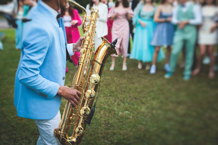 Concert view of saxophonist, a saxophone sax player with vocalist and musical band during jazz orchestra show performing music on a stage in the scene lightsの写真素材