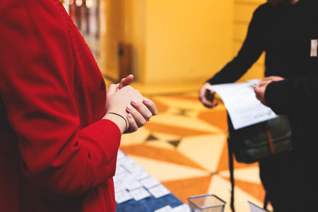 Process of checking in on a conference congress forum event, registration desk table, visitors and attendees receiving the name badge and entrance wristband bracelet and register electronic ticketの写真素材