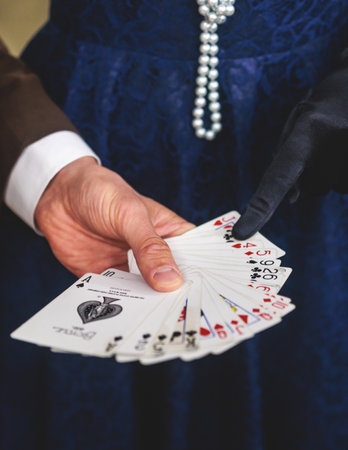 Magician illusionist with a deck of cards showing card tricks focus in front of wealthy rich guests on party event wedding celebration, juggler show, prestidigitator performance on stageの写真素材