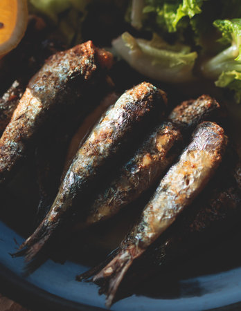 Close-up of traditional greek dish - grilled sardines, roasted sardinas on a plate with potatoes and...