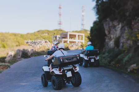 Group of riders riding ATV vehicle crossing mountain serpentine road track, process of driving...