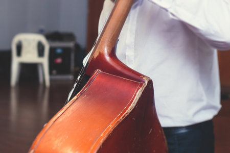 Contrabass cellist player in headphones during rehearsal, recording sound for new album song at studio, cello violoncellist musician with microphone and a musical band orchestra, music productionの写真素材
