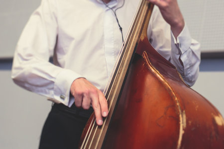 Contrabass cellist player in headphones during rehearsal, recording sound for new album song at studio, cello violoncellist musician with microphone and a musical band orchestra, music productionの写真素材