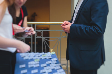 Process of checking in on a conference congress forum event, registration desk table, visitors and attendees receiving a name badge and entrance wristband bracelet and register an electronic ticketの写真素材
