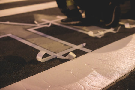 Process of making new road surface markings with a line striping machine, workers improve city infrastructure, demarcation marking of pedestrian crossing with hot melted paint on asphalt pavementの写真素材