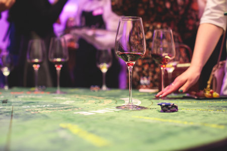 Casino concept, casino table with roulette in motion, with casino chips, tokens, the hand of croupier, dollar bill money and a group of gambling rich wealthy people playing bet in a backgroundの写真素材