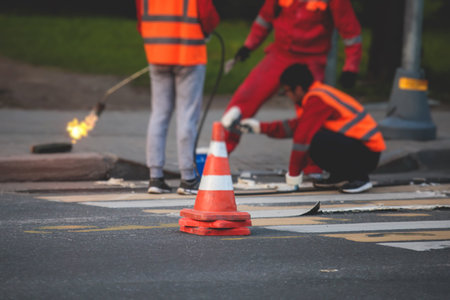 Process of making new road surface markings with a line striping machine, workers improve city infrastructure, demarcation marking of pedestrian crossing with a hot melted paint on asphalt pavementの写真素材