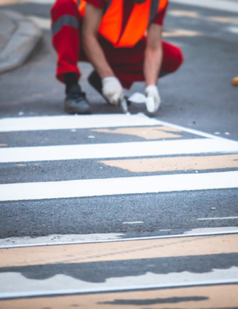 Process of making new road surface markings with a line striping machine, workers improve city infrastructure, demarcation marking of pedestrian crossing with a hot melted paint on asphalt pavementの写真素材