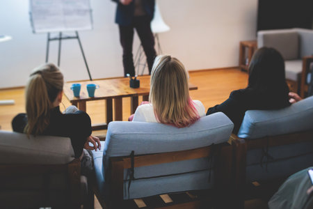Female participants audience at the symposyum meeting, attendees in a conference room hall listens to lecturer, group of women on a congress together listen to speaker on a stage at master-classの写真素材