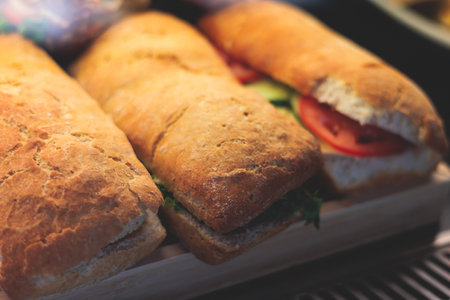 Beautifully decorated catering banquet table with different food snacks and appetizers setting with sandwiches, bagels, baguette club submarine sandwich, on wooden plate, on party or celebrationの写真素材