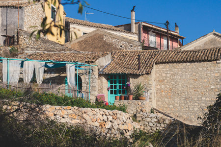 Beautiful view of Lakones streets and houses, traditional greek village near Paleokastritsa, Corfu island, Kerkyra, Ionian sea islands, Greece, in summer sunny day with a blue sky and mountainsの写真素材