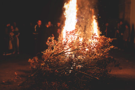 Orthodox Christmas celebration in Montenegro and Serbia, process of burning the Badnjak, fire with oak tree logs and branch during Badnji dan, the Christmas Eve, a bonfire, church and people aroundの写真素材