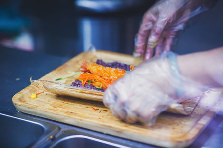 Preparation of a sushi roll in restaurant, close up view on chef handsの写真素材