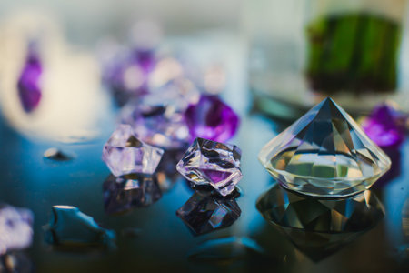 Diamond (small purple jewel) stones heap over mirror glass table, crystal stones, shiny gold and silver jewelery on a tableの写真素材