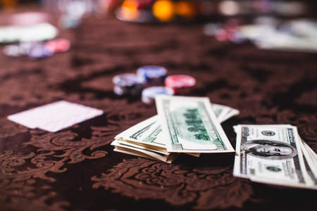 View of poker table with pack of cards, tokens, alcohol drinks, dollar money and group of gambling rich wealthy people playing pokerの写真素材