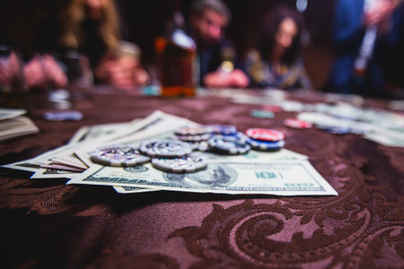 View of poker table with pack of cards, tokens, alcohol drinks, dollar money and group of gambling rich wealthy people playing pokerの写真素材