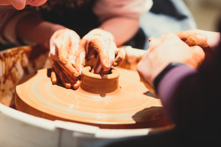 A process of pottery, with two people involved, working on pottery wheel and making clay pot