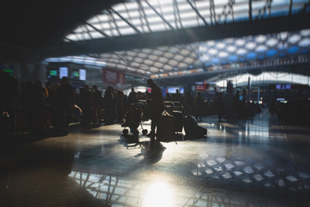 Indoor view of passenger terminal with people silhouettes walking by, train railway station with traveler silhouette crowd, modern terminus interiorの写真素材