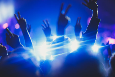 A crowded concert hall with stage stage lights, rock show performance, with people silhouettes...